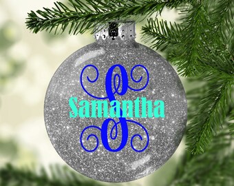 May include: Silver glitter Christmas bauble with a blue and turquoise monogram "S" and the name "Samantha" written in turquoise.