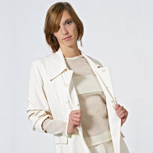 May include: A white blazer with a double-breasted closure and a white sheer top underneath.