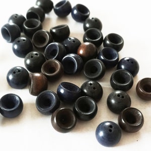 May include: A collection of dark blue and brown wooden buttons with two holes each. The buttons are arranged in a random pattern on a white surface.