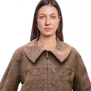 May include: A brown corduroy jacket with a large collar and a zip fastening. The jacket has a textured fabric and a relaxed fit.