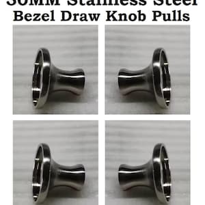 May include: Four 30MM stainless steel bezel draw knobs shown in a grid. Each knob features a polished metallic finish with a circular bezel top and a tapered stem, designed for attachment to furniture or cabinetry hardware.