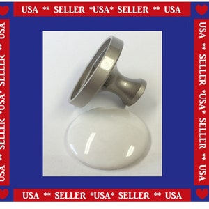 May include: A silver-toned cabinet knob with a white, oval-shaped ceramic base. The knob has a circular handle and a stem. The image has a red, white, and blue border with the text "USA ** SELLER *USA* SELLER ** USA".