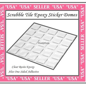 May include: A sheet of clear resin epoxy sticker domes for Scrabble tiles. The domes are arranged in a grid pattern and are designed to protect and enhance the appearance of Scrabble tiles.