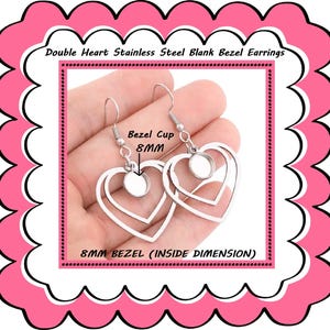 May include: Stainless steel double heart earrings with blank bezel cups. The earrings have a heart-shaped design with an 8mm bezel cup. The text on the image reads "Double Heart Stainless Steel Blank Bezel Earrings" and "8MM BEZEL (INSIDE DIMENSION)".