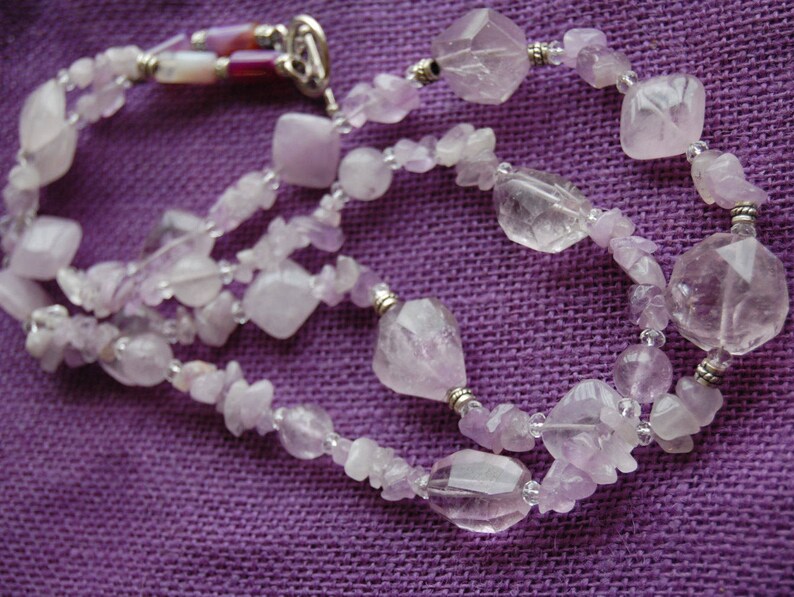 May include: A multi-strand necklace made of light purple amethyst beads of various shapes and sizes. The necklace is made of both smooth and faceted beads, and is accented with silver beads.