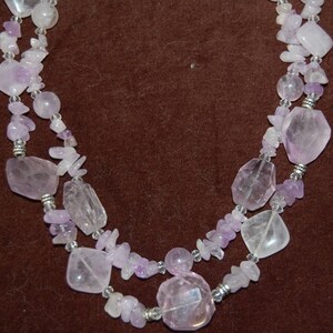 May include: A double-strand necklace made of light purple and clear faceted gemstone beads. The necklace is made of various shapes and sizes of beads.