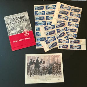 May include: A collection of vintage stamps, including Apollo Soyuz 1975 and a historical scene of Washington reviewing his ragged army. Also, a red and white "Stamp Collecting" merit badge book from the Boy Scouts of America.