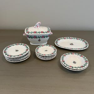 May include: A vintage porcelain tea set with a floral design. The set includes a covered teapot, a serving platter, and eight small bowls.