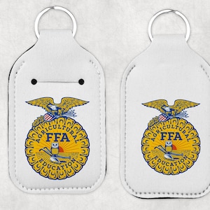 May include: Two white keychains with a metal ring at the top. Each keychain features a yellow and blue FFA emblem with an eagle, the words "AGRICULTURAL EDUCATION" and "FFA".