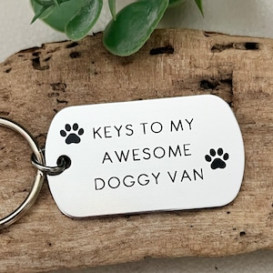 Peut inclure: Porte-clés en métal argenté avec une empreinte de patte noire et le texte "KEYS TO MY AWESOME DOGGY VAN".
