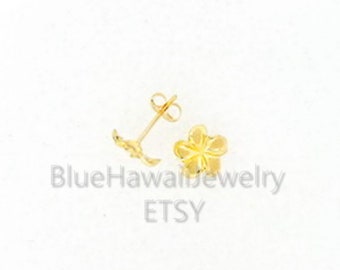 May include: A pair of gold-colored flower stud earrings. One earring is a post with a curved design, and the other is a detailed flower shape. The earrings are on a white background. The text "BlueHawaiiJewelry" and "ETSY" are visible.