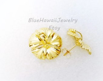 May include: A pair of gold-colored hibiscus flower stud earrings. The earrings are detailed with textured petals and a post backing. The image includes the text "BlueHawaiiJewelry Etsy".