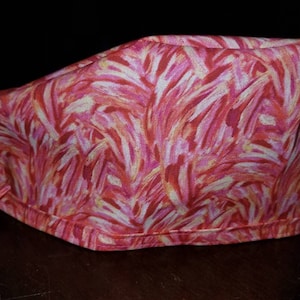 Puede incluir: Un gorro quirúrgico de color rosa y blanco con un patrón y una corbata en la parte posterior.