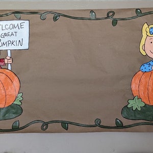 Może przedstawiać: Brązowy baner z postaciami z kresk&oacute;wek i dyniami. Jedna postać trzyma znak z napisem "WELCOME GREAT PUMPKIN". Baner ma zieloną obw&oacute;dkę z liśćmi, idealny na Halloween lub jesień.
