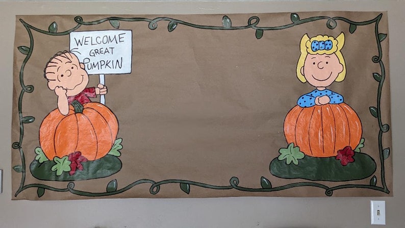 Może przedstawiać: Brązowy baner z postaciami z kresk&oacute;wek i dyniami. Jedna postać trzyma znak z napisem "WELCOME GREAT PUMPKIN". Baner ma zieloną obw&oacute;dkę z liśćmi, idealny na Halloween lub jesień.