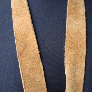 May include: A long, brown suede strap, possibly for a bag or purse.