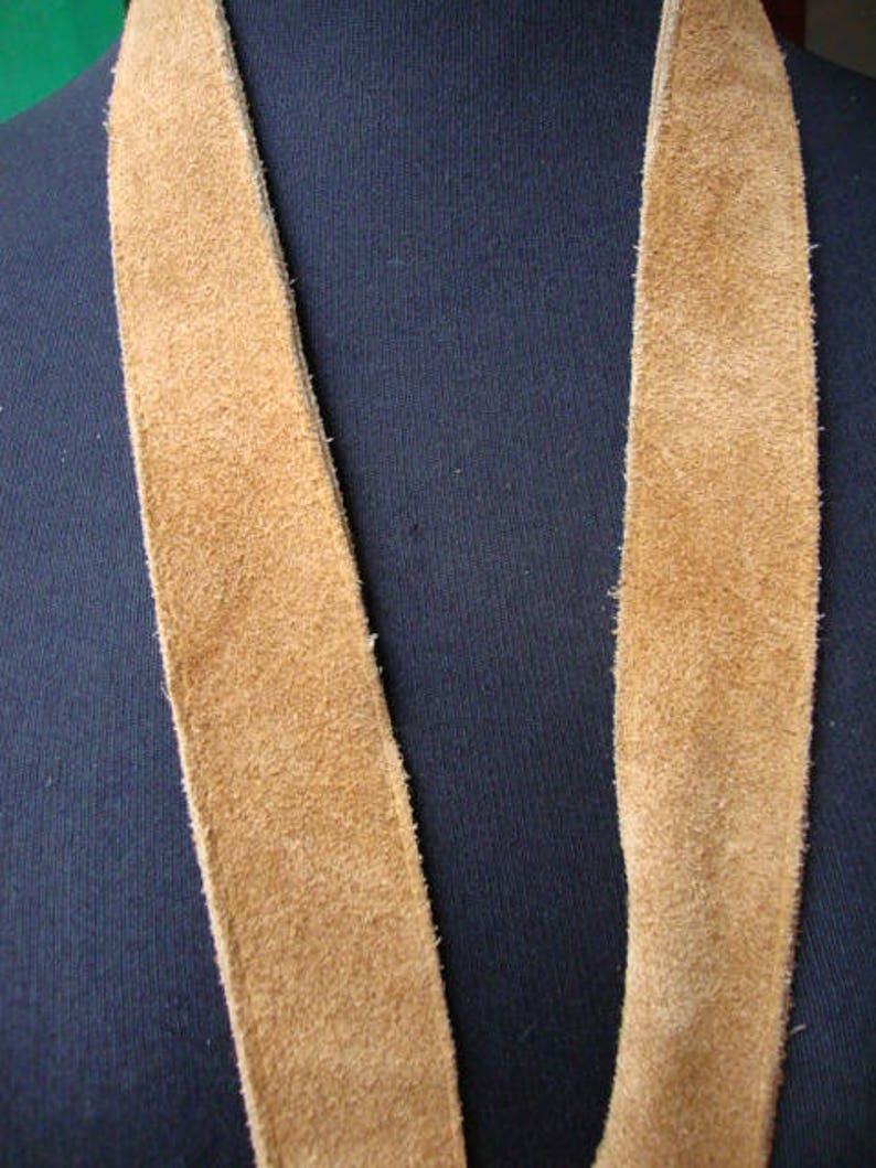 May include: A long, brown suede strap, possibly for a bag or purse.