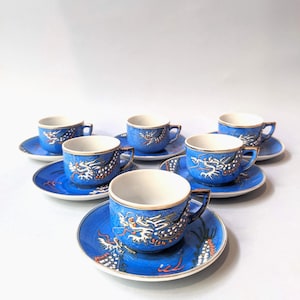 Könnte beinhalten: Satz mit sechs blauen und weißen Teetassen und Untertassen mit goldfarbenem Rand und Drachenmotiv.