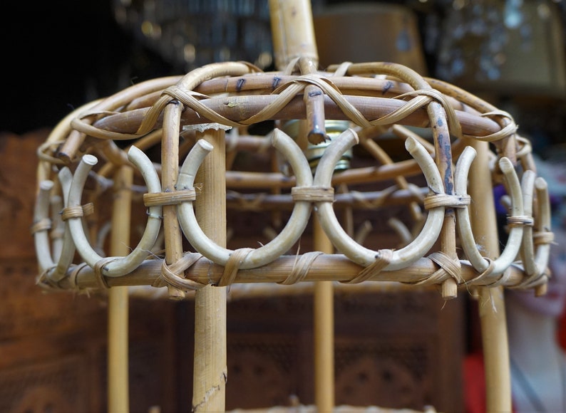 May include: A woven bamboo lampshade with a circular design. The lampshade is made of natural materials and has a rustic look.