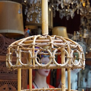 May include: A woven bamboo pendant light fixture with a circular design. The fixture has a natural wood finish and is suspended from a single cord.