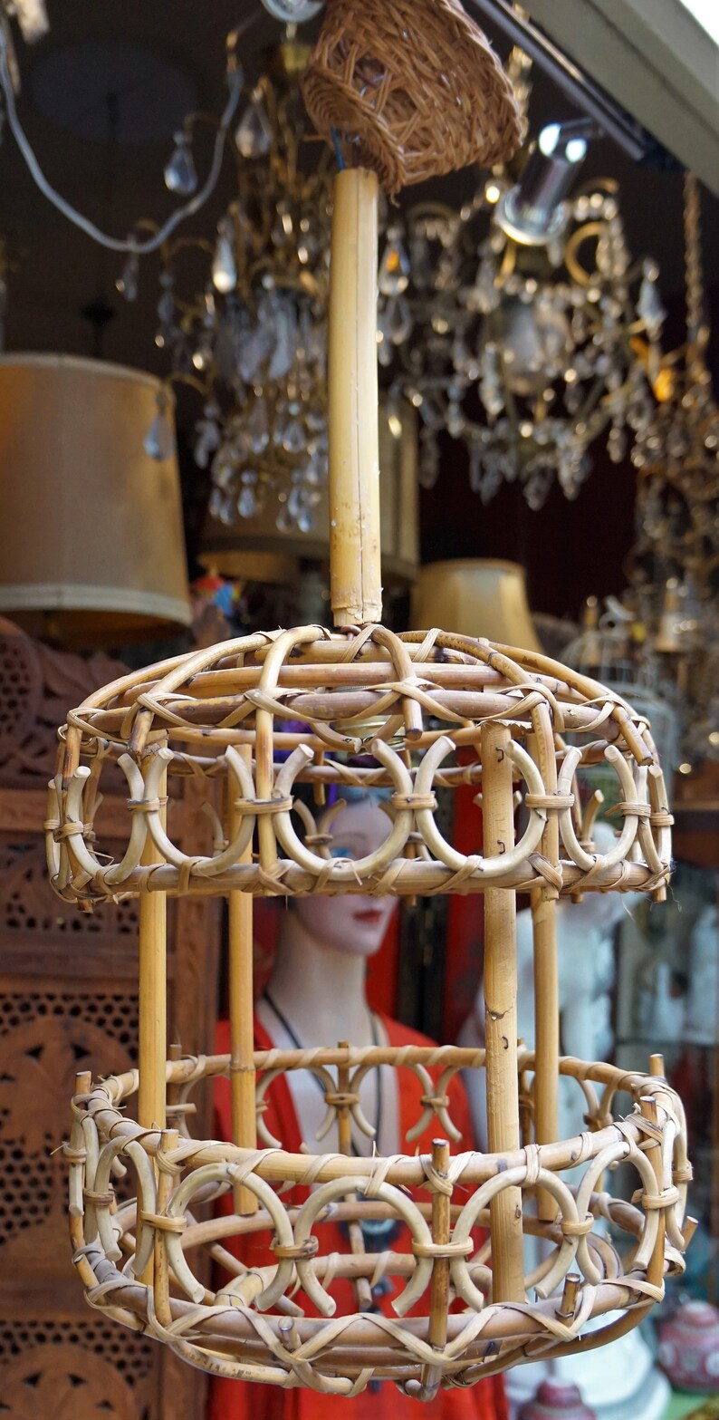 May include: A woven bamboo pendant light fixture with a circular design. The fixture has a natural wood finish and is suspended from a single cord.