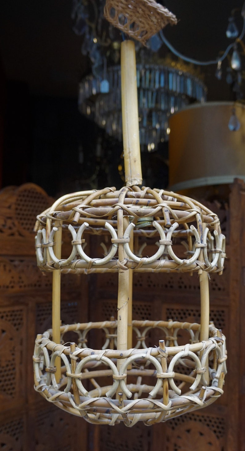 May include: A woven wicker pendant light fixture with a round, open design. The light fixture is made of natural brown wicker and has a simple, rustic style.