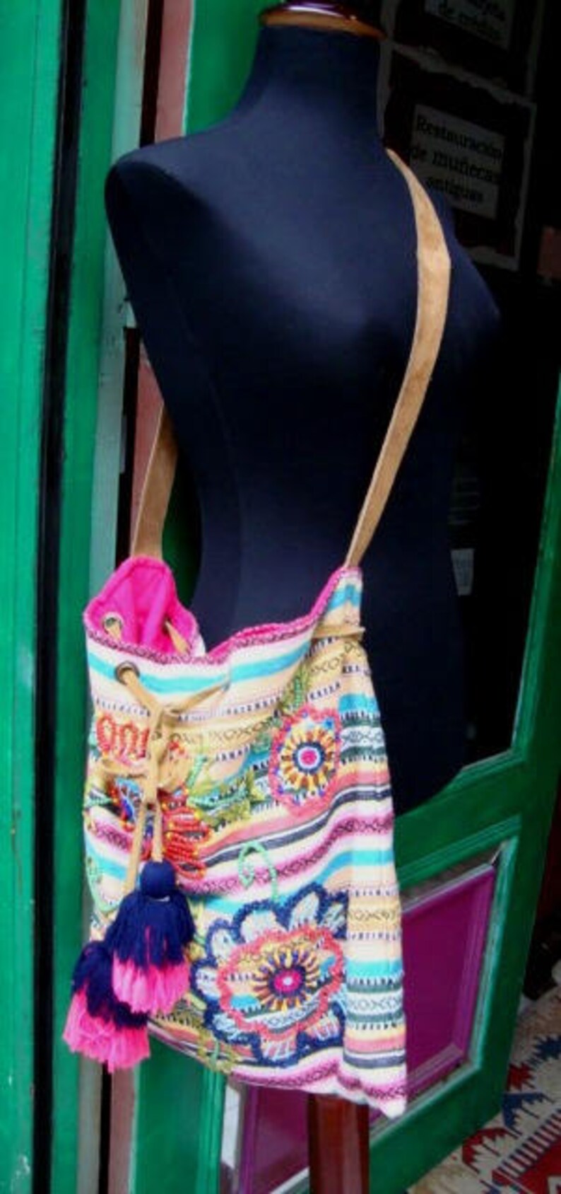 May include: A colorful striped and embroidered tote bag with pink, blue, and yellow accents. The bag has a brown leather strap and a pink lining.