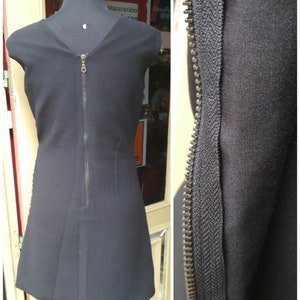 May include: A black sleeveless dress with a zipper down the back. The zipper is visible in a close-up view.