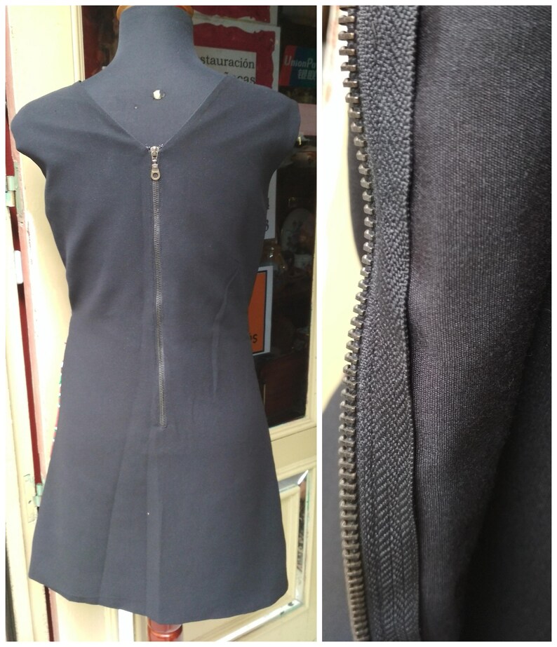 May include: A black sleeveless dress with a zipper down the back. The zipper is visible in a close-up view.