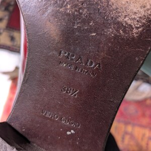 May include: Close-up of a brown leather shoe sole with the embossed text "PRADA MADE IN ITALY". The size is marked as 38 1/2. The words "VERO CUOIO" are also visible.