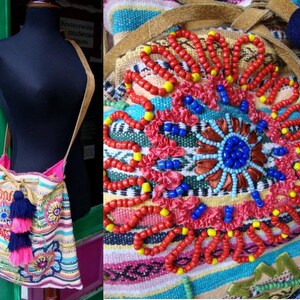May include: A colorful woven bag with a drawstring closure and a long strap. The bag is decorated with embroidered flowers and beads in shades of red, blue, yellow, and pink.