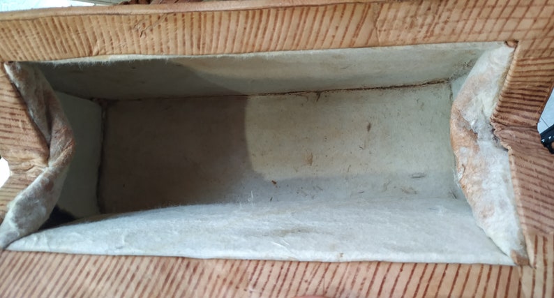 Puede incluir: El interior de una peque&ntilde;a caja rectangular con un exterior marr&oacute;n claro y un forro de tela blanco. La caja est&aacute; vac&iacute;a.