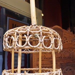 May include: A woven bamboo pendant light fixture with a circular shape and a woven basket on top. The light fixture is hanging from a ceiling.