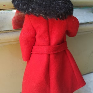 May include: A red coat with a black fur collar. The coat has a belt and is made of a soft, fuzzy fabric.