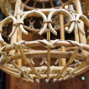May include: A close-up of a woven wicker lampshade. The lampshade is made of natural brown bamboo and has a round shape.
