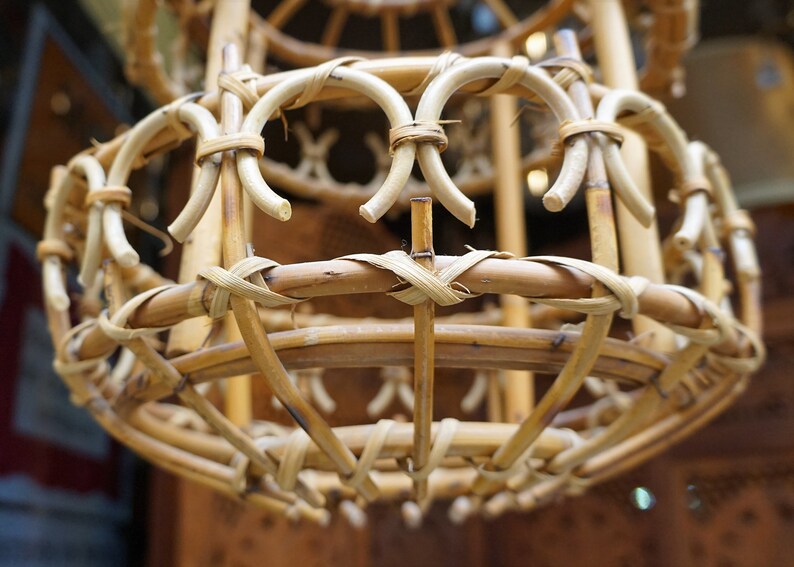 May include: A close-up of a woven wicker lampshade. The lampshade is made of natural brown bamboo and has a round shape.