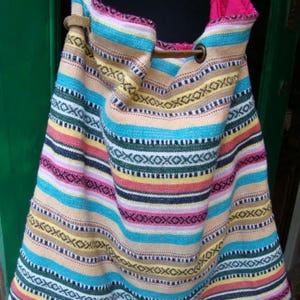 May include: A colorful striped tote bag with a leather strap and a metal buckle. The bag is made of woven fabric and has a bright, vibrant pattern.