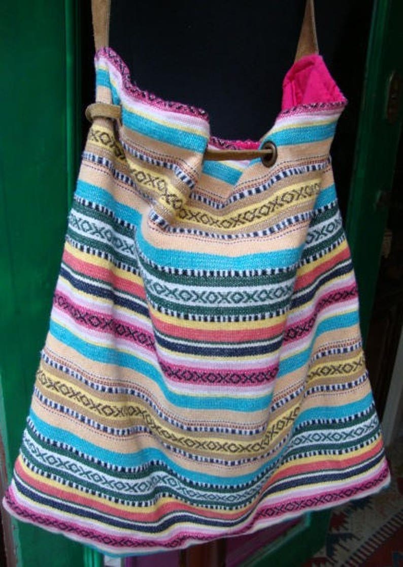 May include: A colorful striped tote bag with a leather strap and a metal buckle. The bag is made of woven fabric and has a bright, vibrant pattern.
