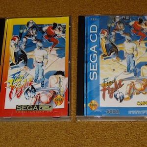 May include: Two Sega CD game cases for Final Fight CD. The cases are blue and yellow with the game title and Sega logos. The front of the cases feature artwork of characters from the game.