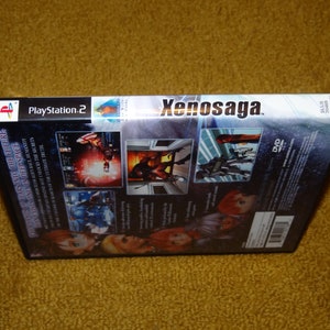 May include: A black PlayStation 2 game case with a silver spine. The game is Xenosaga, and the case has a DVD logo and a barcode. The back of the case features screenshots of the game and text in English.