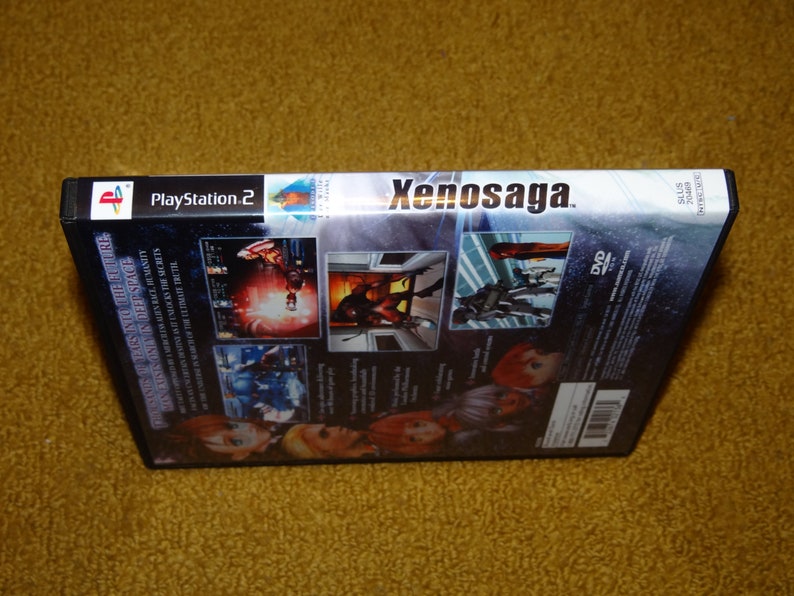 May include: A black PlayStation 2 game case with a silver spine. The game is Xenosaga, and the case has a DVD logo and a barcode. The back of the case features screenshots of the game and text in English.
