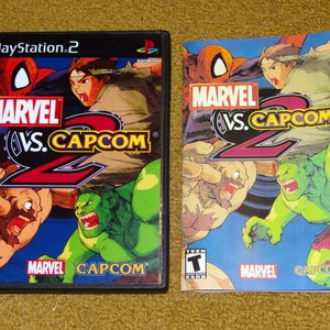 May include: A PlayStation 2 video game case for Marvel vs. Capcom 2. The case is black with a colorful image of characters from the game, including Spider-Man, Ryu, Hulk, and  a character from the Street Fighter series. The game is rated T for Teen by the ESRB.