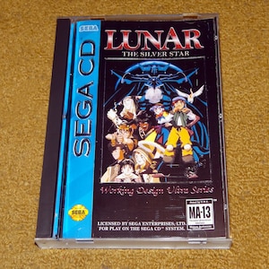 May include: A Sega CD game case for Lunar: The Silver Star. The case is blue and black with a picture of the game's characters on the front. The game is rated MA-13.