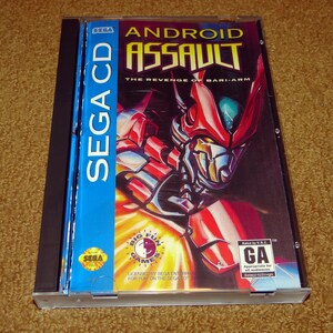 May include: A Sega CD game case for Android Assault: The Revenge of Bari-Arm. The case is blue and black with a red and silver robot on the front. The game is rated GA for all audiences.
