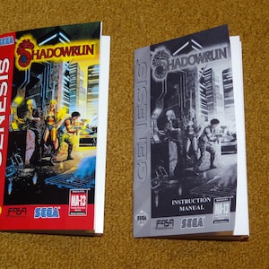 May include: Two SEGA Genesis game boxes, one red and one gray, featuring the game "Shadowrun." The red box has a colorful illustration of characters in a futuristic setting. The gray box is a black and white version with the text "Instruction Manual."