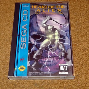 May include: A Sega CD game case for "Heart of the Alien: Out of This World Parts 1 and 2". The cover art features a muscular, green-skinned alien holding a whip, standing on a skull with lightning bolts in the background. The case is blue and has the Sega logo on it. The game is rated MA-13.