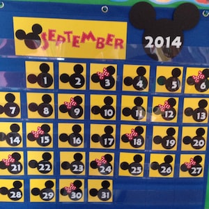 May include: A yellow and black Mickey Mouse themed calendar for September 2014. Each day is represented by a square with a Mickey Mouse head, some with a red bow.