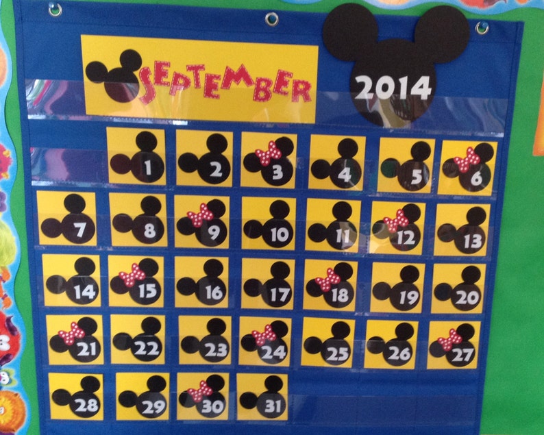 May include: A yellow and black Mickey Mouse themed calendar for September 2014. Each day is represented by a square with a Mickey Mouse head, some with a red bow.