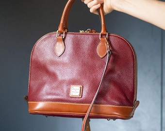 Dooney & Bourke leren handtas in bordeauxbruin, ideaal als cadeau. Middelgrote schoudertas voor dames met messing details. Afneembare schouderriem.