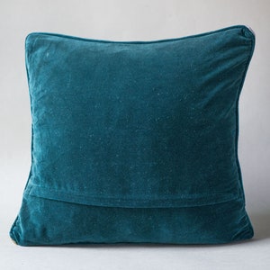 May include: A teal blue velvet pillow with a seam down the center.